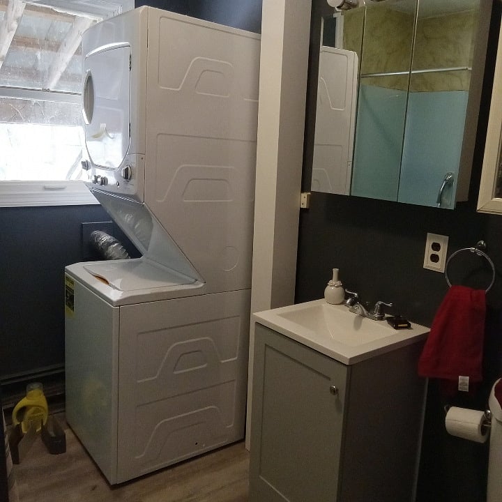 Bathroom with full tub, shelf and cabinet storage, compact washer/dryer