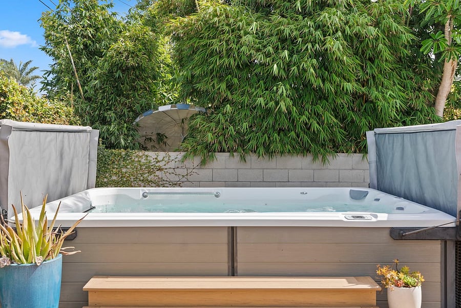 Unwind in the private hot tub surrounded by lush greenery and enjoy a peaceful outdoor retreat.