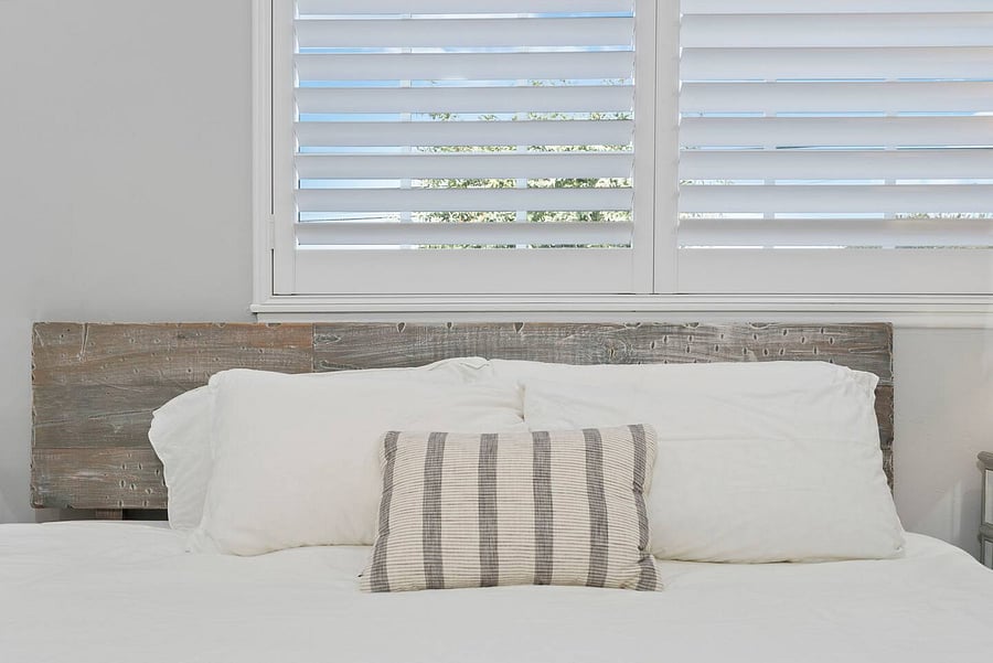 Sleep soundly in the comfortable king bed featuring soft linens, a rustic wood headboard, and stylish accent pillows.