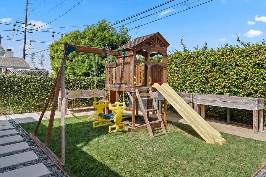 Let the little ones play in the private yard featuring a playset, swings, slide, and spacious grassy area.