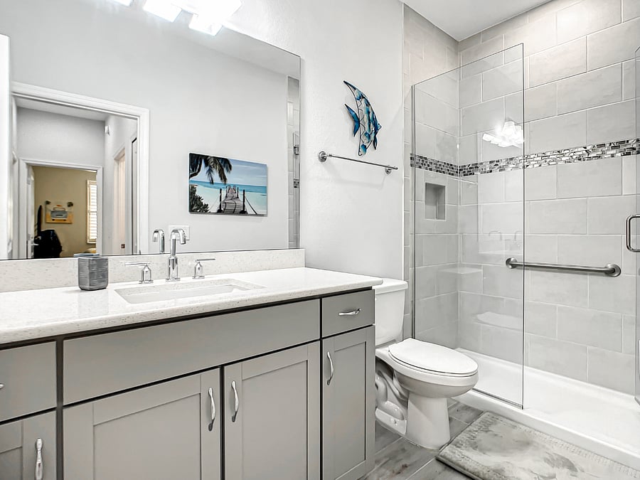 Guest bathroom with quartz countertop and walk-in shower with frameless glass shower enclosure.