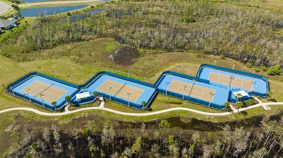 Aerial view of outdoor lighted tennis courts and partial view of walking trail.