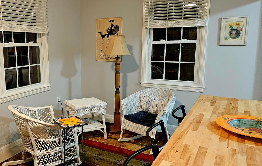 Butcher block island in kitchen and small sitting area with wicker chairs and table