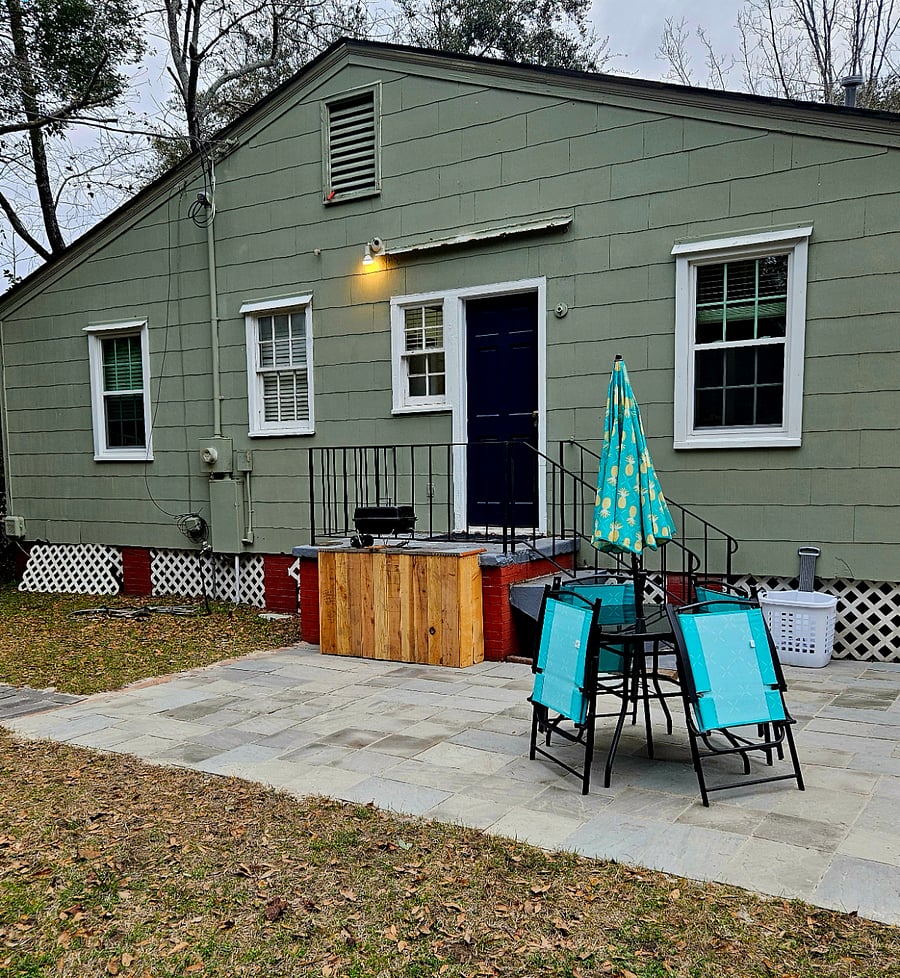 Back patio with small and large grills and outdoor table with chairs and umbrella