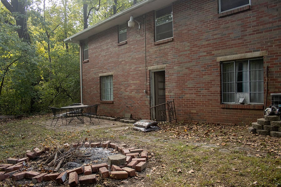 Back yard surrounded by woods on two sides and a large grass lot between next neighbor to left of house. 