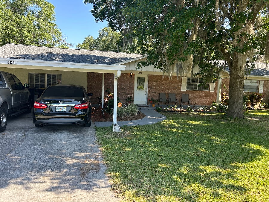 Front of house showing parking space under carport for sun and rain protection. Keypad entrance into home and security system for safety. 