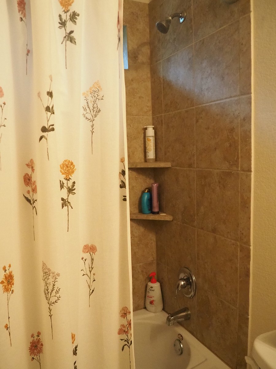 Full sized shower and bathtub equip with shampoo, conditioner, and bodywash.