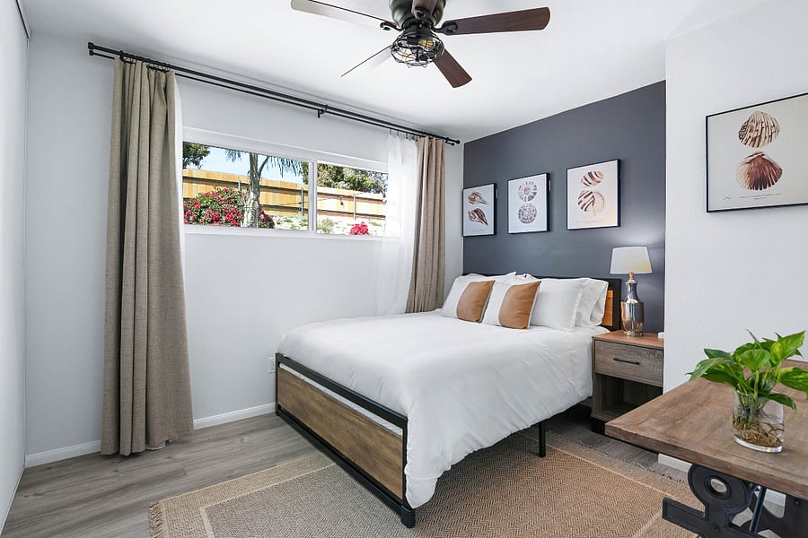 Bedroom includes a queen sized, plush bed with blackout curtains, electronic charging dock, full length mirror, and luggage rack.
