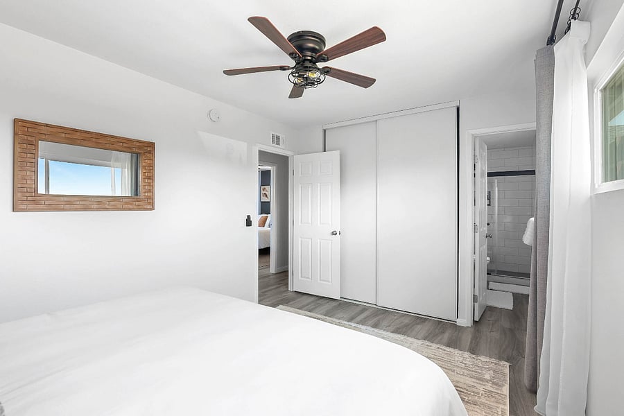 View from corner of room showing door leading to hallway on the left (view of bedroom 1) and private en-suite bathroom on the right. Luggage rack located in closet.