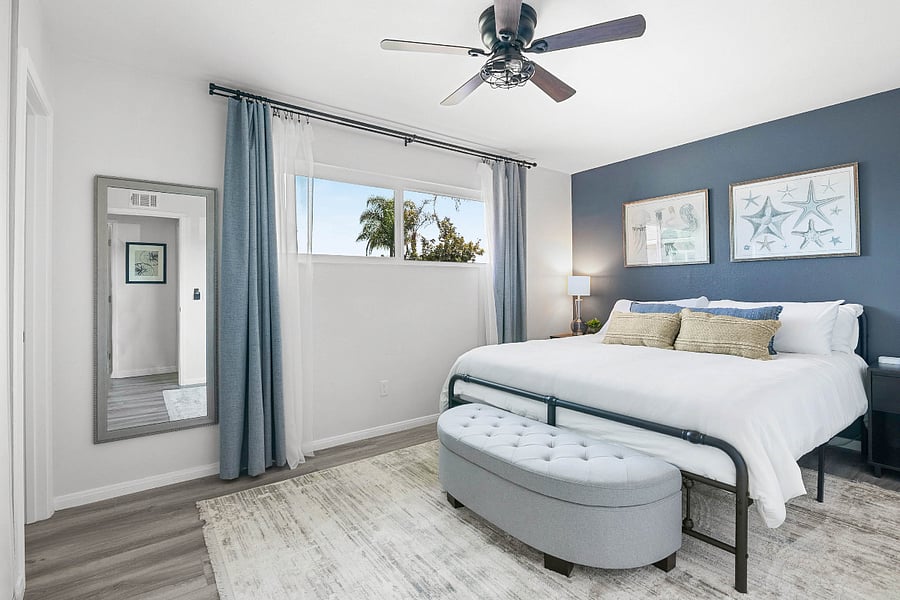 Bedroom 3 includes a king sized plush bed, blackout curtains, full length mirror, and ottoman with storage.