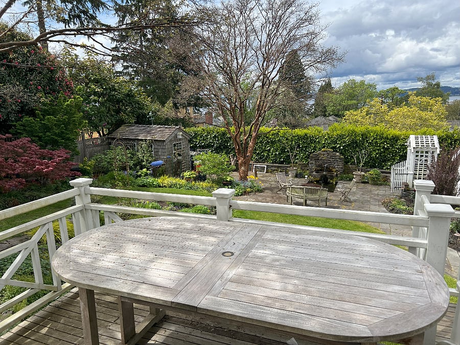 Table, chairs and view to the west of gardens, and Olympic Mountains and Puget Sound in the distance