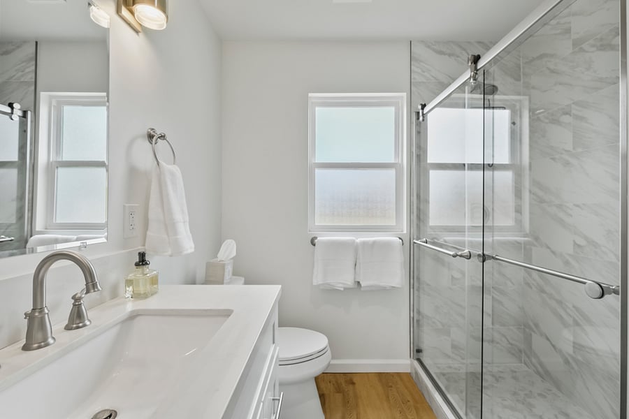 Glass shower doors with marble surrounding shower walls