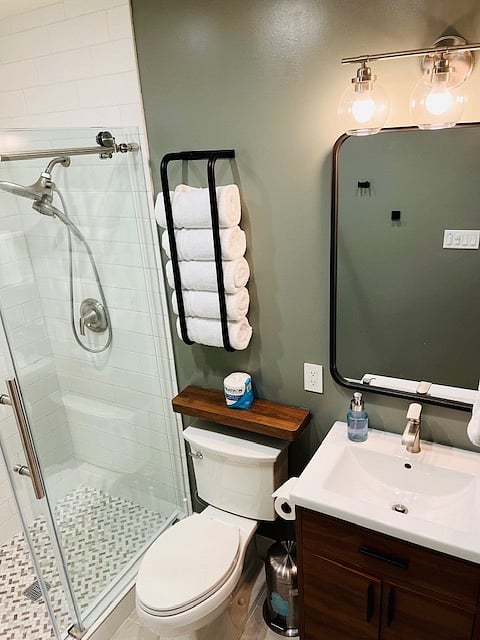 Renovated bathroom with glass door shower and dual head shower.