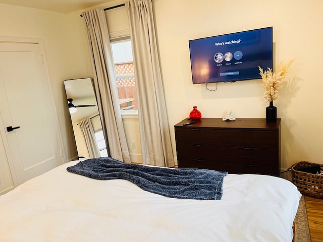 View from the King sized bed. Dresser under wall mounted smart tv. Full length mirror and good sized closet in the bedroom.