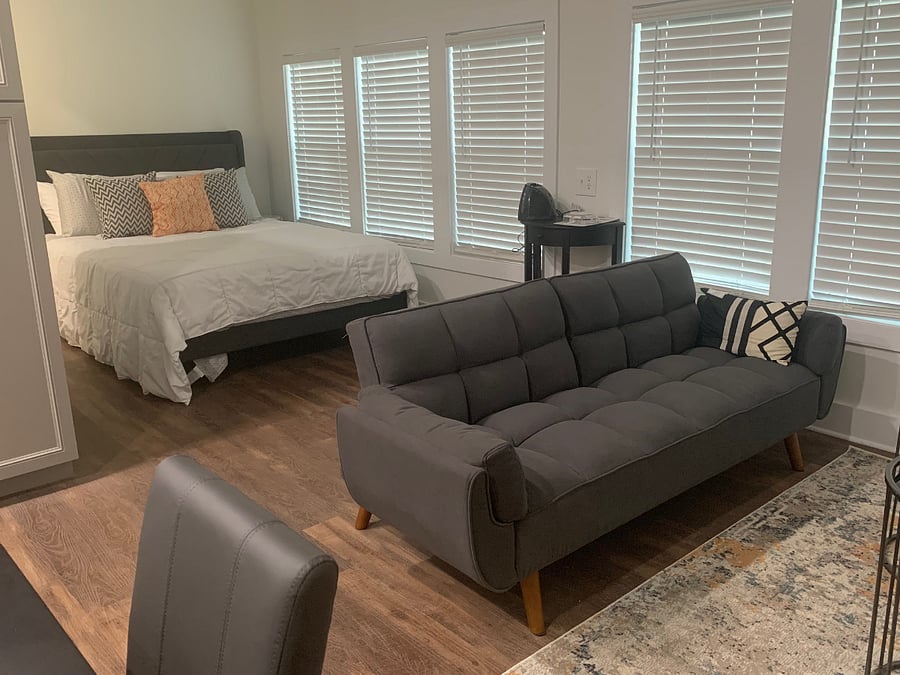 Living and bedroom area with lots of natural light. (Note: blackout curtains and sheers have been installed to block out light and allow light with privacy).