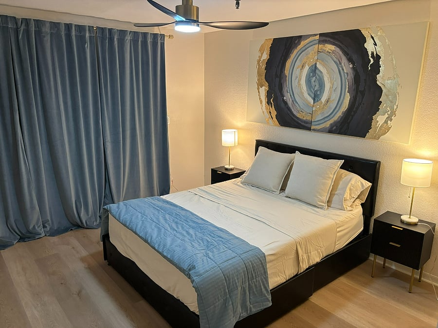 Queen size bed. Behind the curtains are the sliding doors that lead to the balcony.