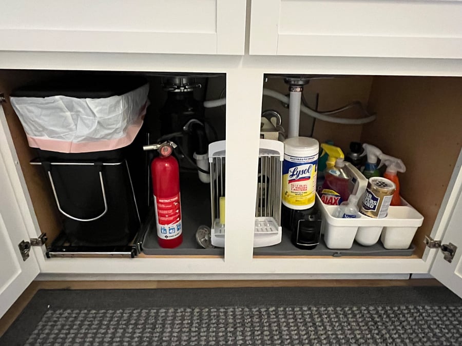 Under counter trash with lid, fire extinguisher, cleaning products, extra dish drying basket.