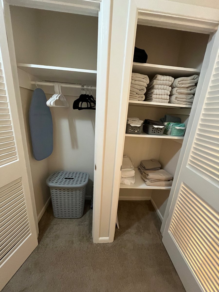 Upstairs storage closets with medium sized ironing board, laundry hamper, and a variety of towels and washcloths.