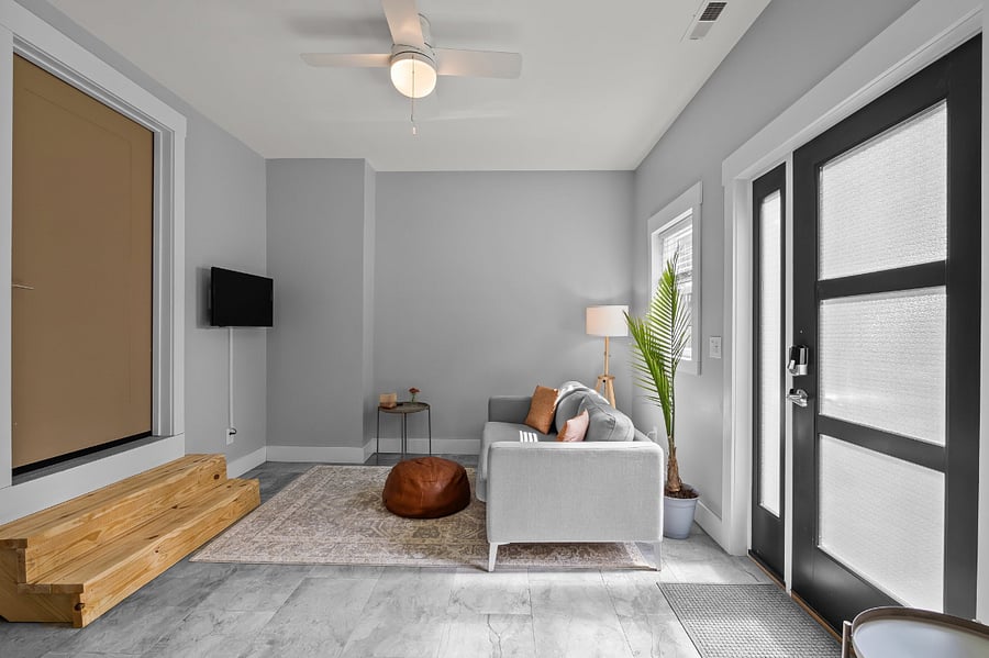 Living room area with sofa, lamp, ottoman, 2 small (portable) side tables, a wall-mounted TV, and a little extra room for your things (like dog kennels, etc).