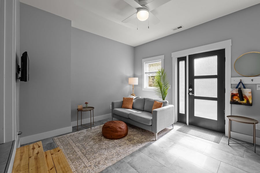 Living room area with sofa, lamp, ottoman, 2 small (portable) side tables, a wall-mounted TV, and a little extra room for your things (like dog kennels, etc).