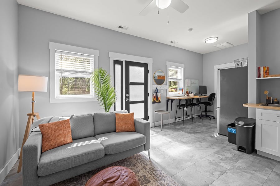 Living room area with sofa, lamp, ottoman, 2 small (portable) side tables, a wall-mounted TV, and a little extra room for your things (like dog kennels, etc).