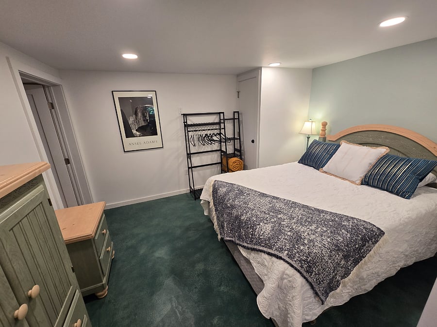 View from kitchen entrance. Queen bed, hanging rack and side of wardrobe shown. Bathroom door is on the left.