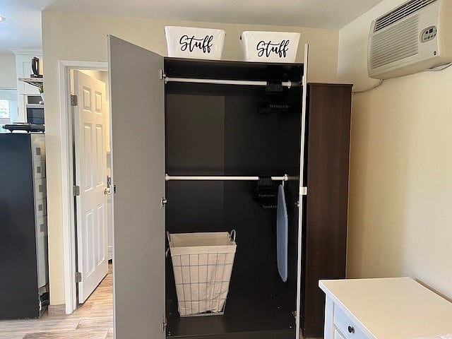 Closet with laundry basket and ironing board.