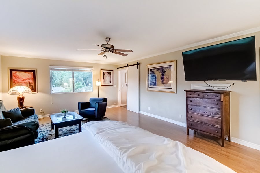 The master bedroom offers generous space, featuring a king-sized bed adorned with luxury linens. It also includes a smart TV, a lounge area with a futon couch, and a nursery for your convenience.
