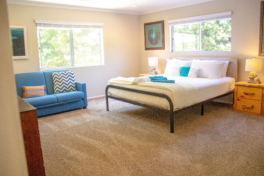 Bedroom 2 features luxurious linens, a TV, and a spacious futon couch, offering ample comfort and relaxation for guests.