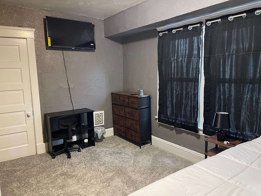 Bedroom 2: Step inside a well-appointed room at Corporate Haven featuring a full-size bed, a spacious closet, and a cozy workspace complete with a desk and chair. The room is equipped with a flat-screen Google TV for your entertainment and a nightstand with a lamp for your reading comfort. Enjoy the convenience of high-speed WiFi, making it perfect for both relaxation and productivity.