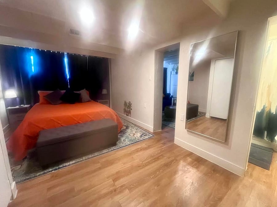 Spacious bedroom with a queen bed, a full-length mirror, ensuite bathroom and barn-style sliding door that opens to the living room for added privacy.
