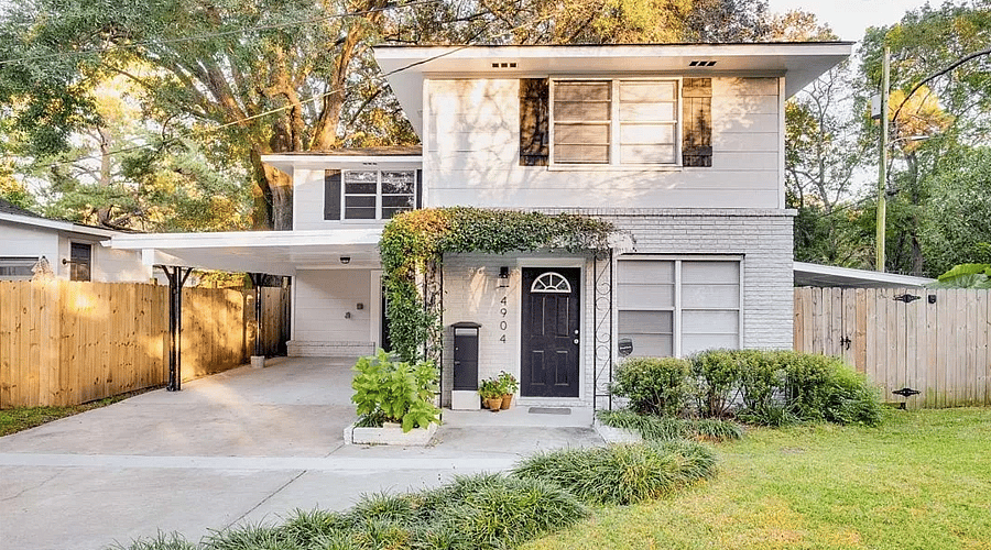 House front with carport. Lush tropical landscaping.