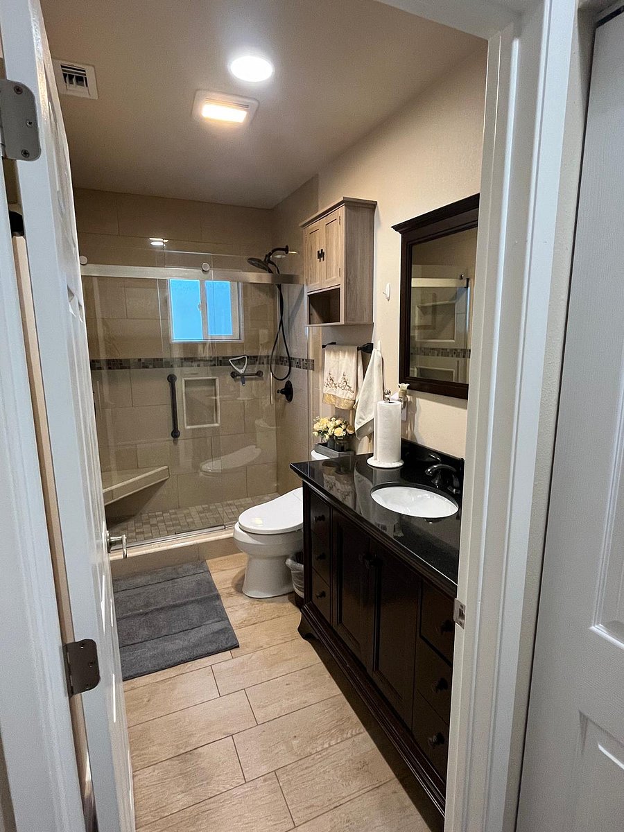 Bathroom with shower, handles, and seating area.