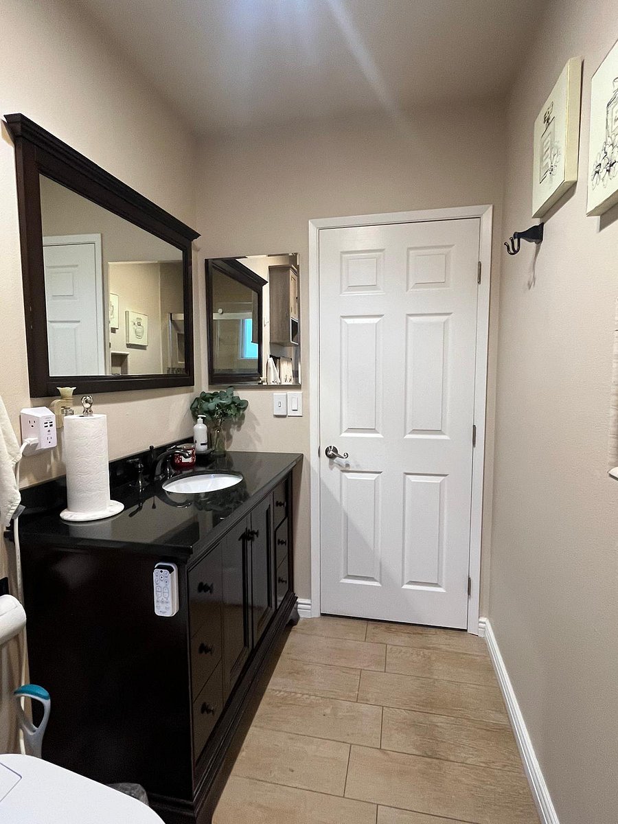 Bathroom with drawers, cabinets, and shower. Shower has handles, seating area, and shelf for bath products.