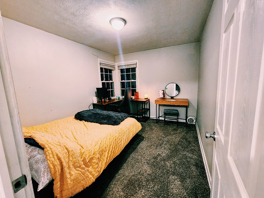 Second bedroom with office desk, monitor, and vanity mirror desk. Has its own closet (behind the door on right).