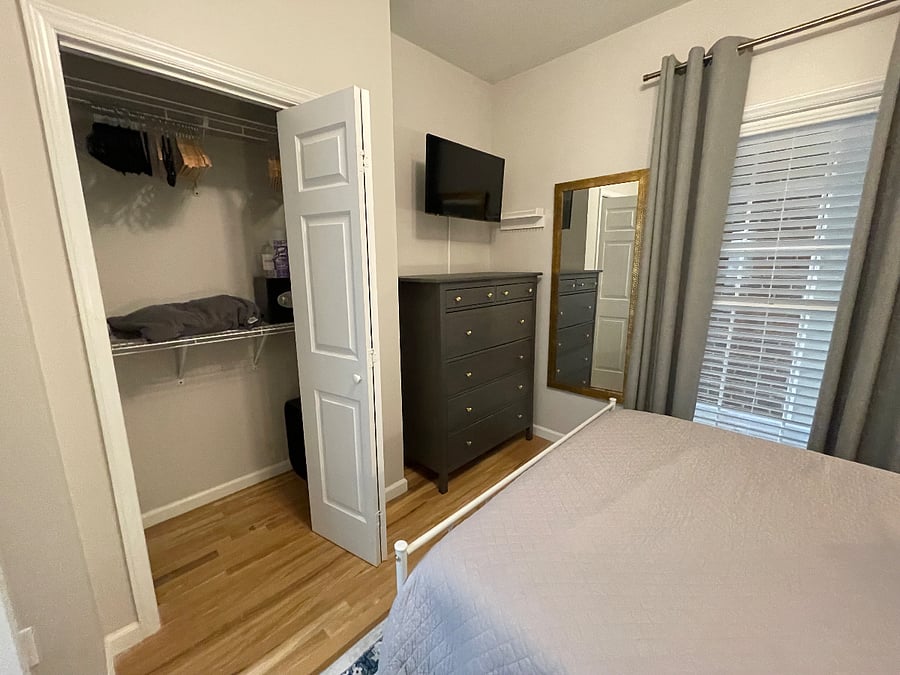 Closet with plenty of hangers, extra bedding, box fan, laundry drying rack, and safe