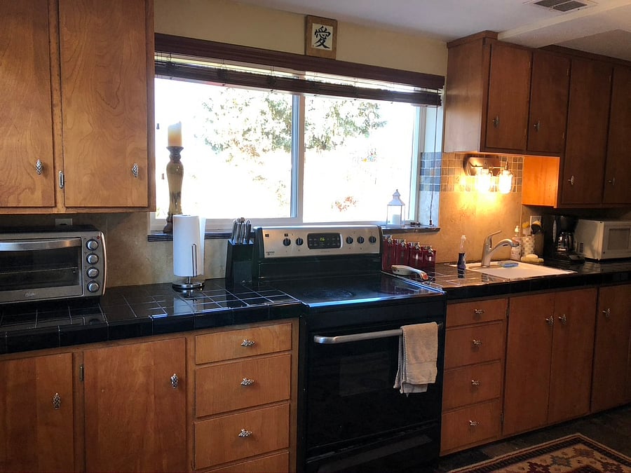 Fully equipped kitchen with large windows, natural light, stove and oven and toaster oven