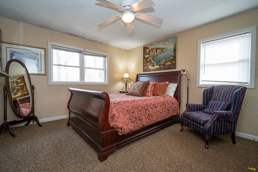 Queen sized bed, Floor mirror, smart tv, dresser, full sized closet, and sitting chair in the bedroom.
