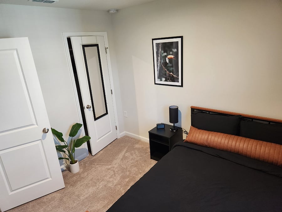 Full-sized bed with memory foam mattress, adjustable lamp, and closet space with hangers located in guestroom.