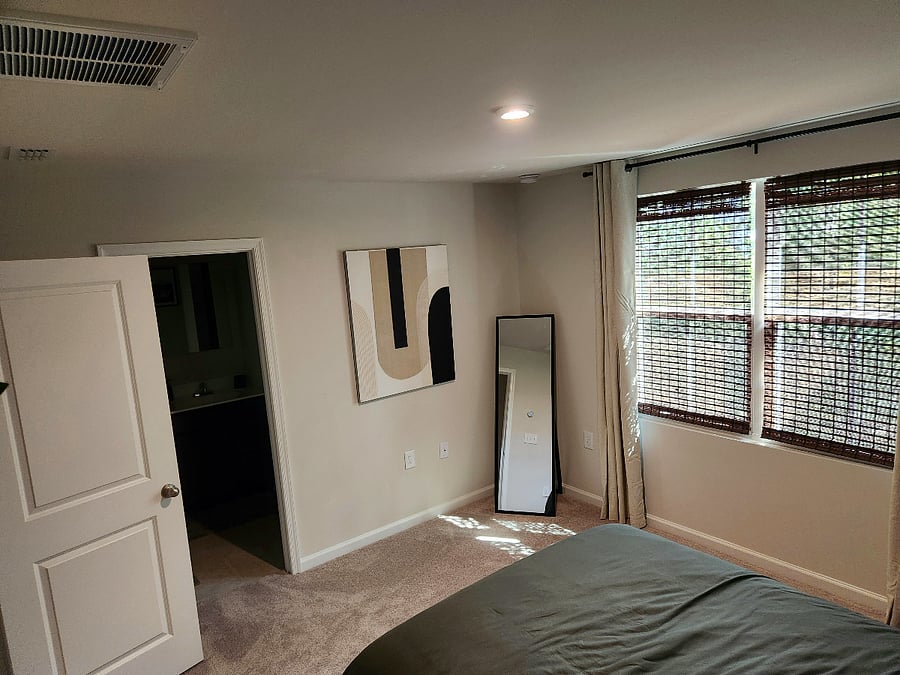 Mid-Century Modern bedroom with comfortable queen bed and full-length mirror.