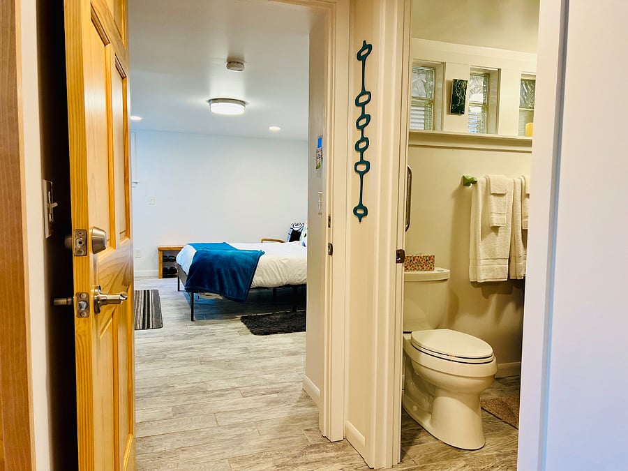 View into bedroom and bathroom from hall outside the kitchen.
