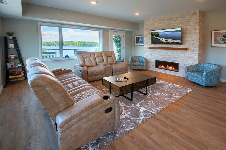 Open living room with fireplace, large smart TV, and access to the wrap around balcony overlooking the lake.