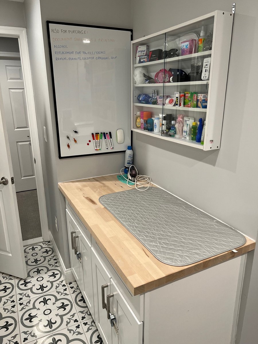 ironing board with iron, folding table, and items for sale to include hygiene products, food, power adapters, sewing kits, sunglasses/slippers, over the counter medicine, flavor for water, cleaning products, toiletries, etc.