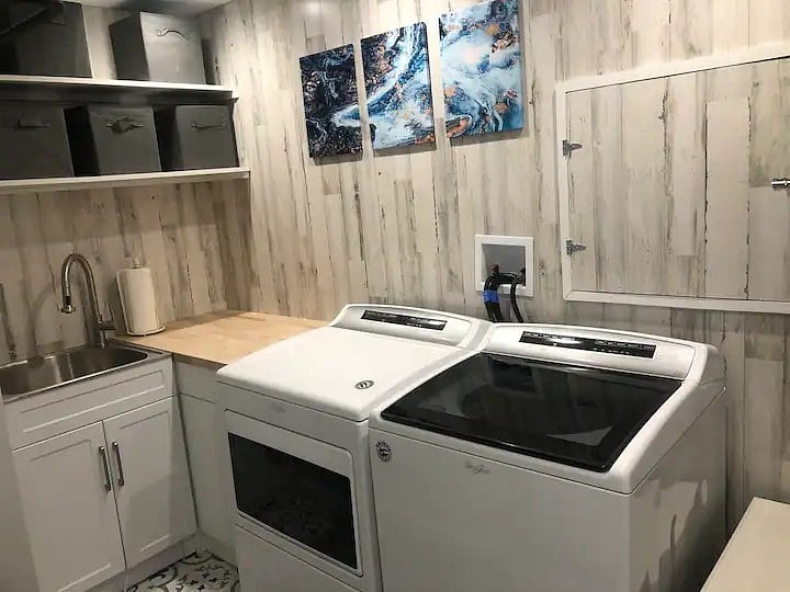 Whirlpool oversized laundry and drier, folding table, ironing board with iron, 24x24 inch utility sink and plenty of storage.