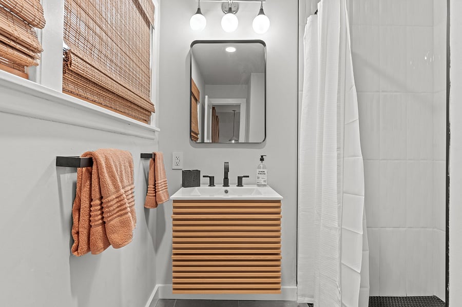 Full set of towels and rattan shades add texture to a modern bathroom. 