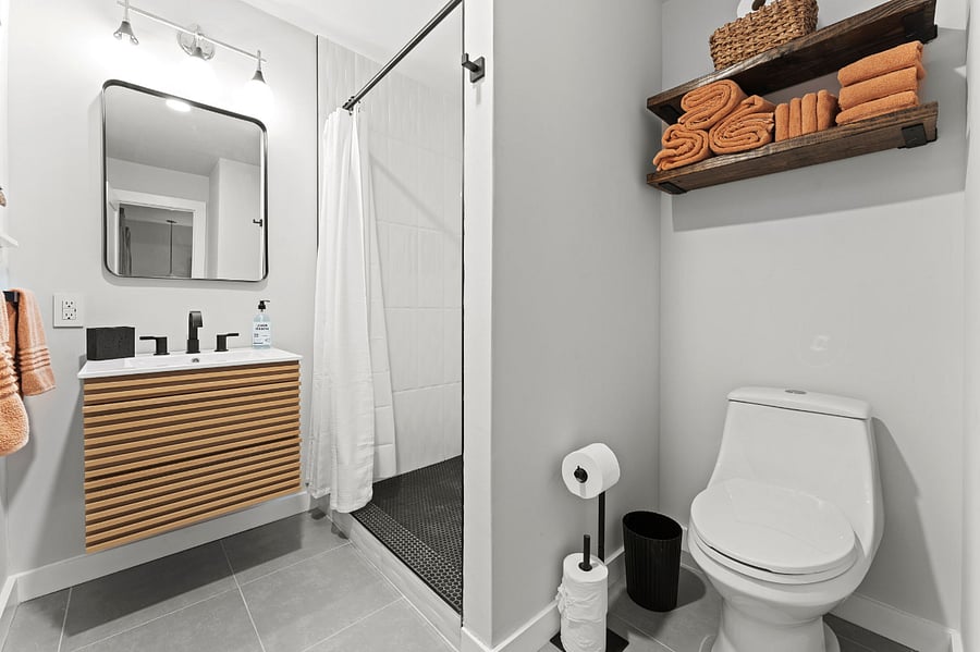 Full-size bathroom includes new toilet and additional storage above. 