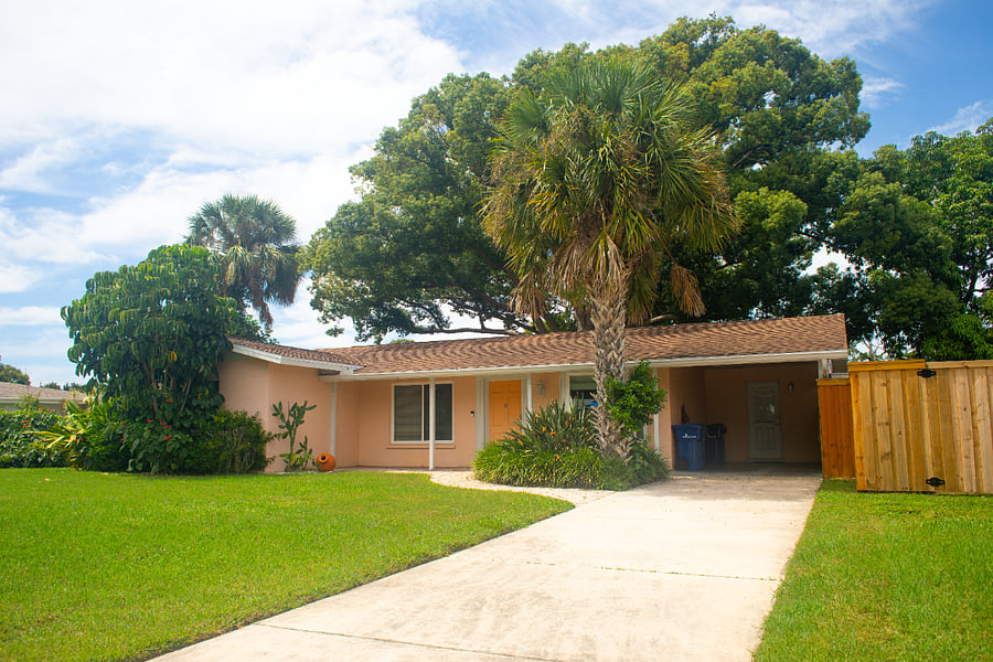 The exterior of the house is framed by lush greenery and mature trees, providing a tranquil and private setting. 
