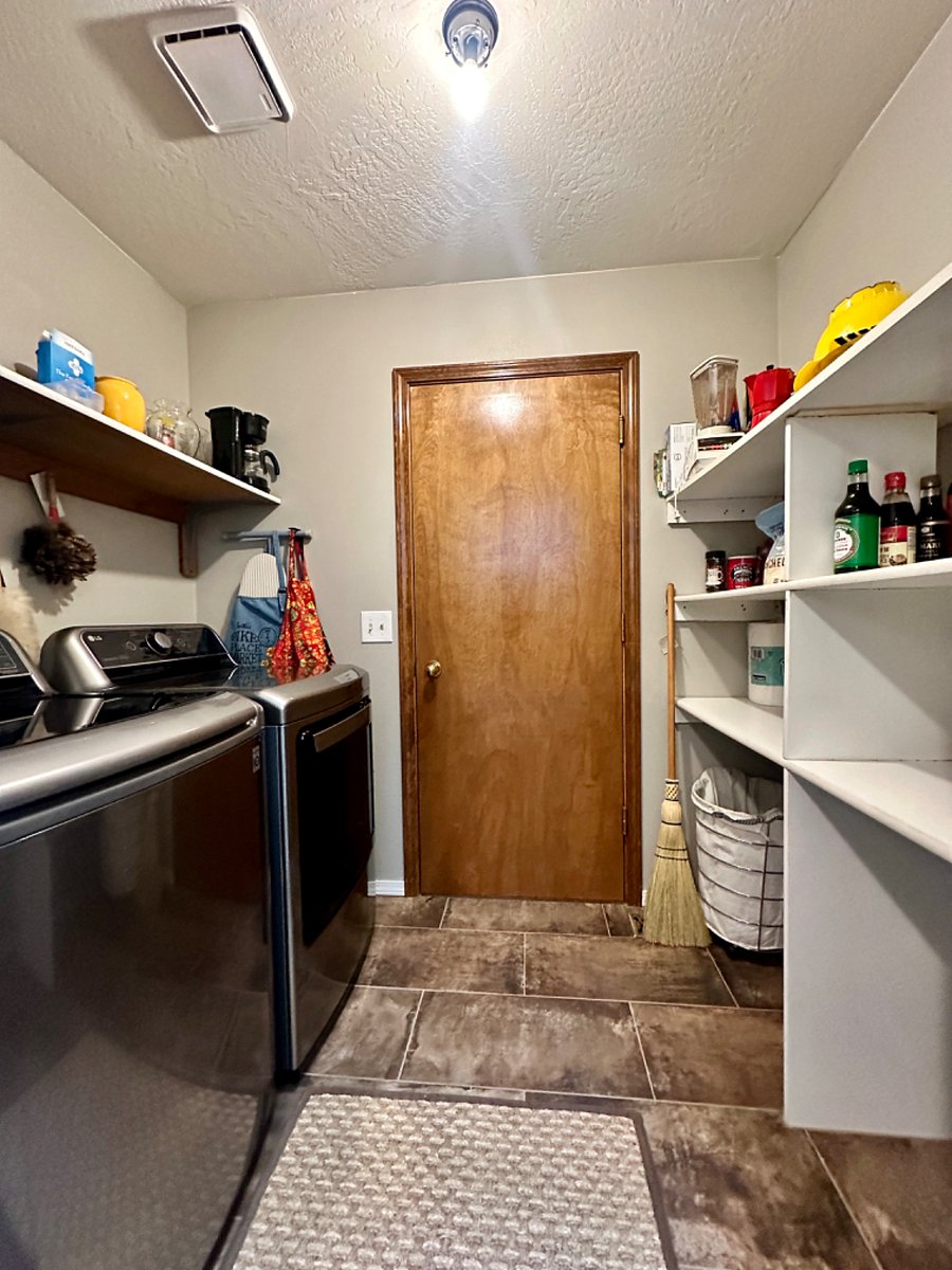 Laundry room with new washer/dryer, storage shelving for supplies.