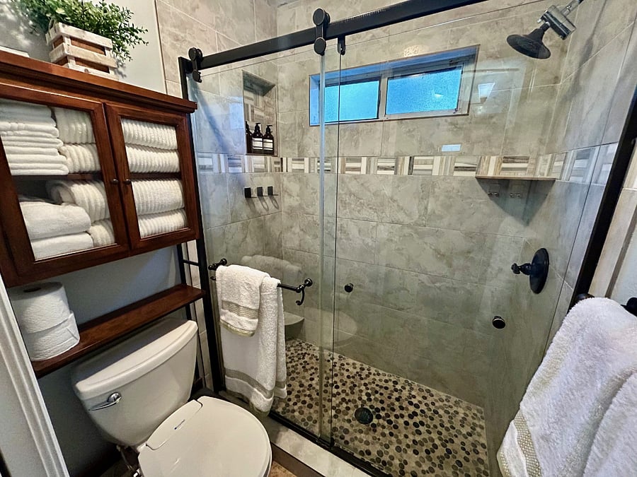 Master bath walk in shower with lots of towels and bidet seat for toilet.