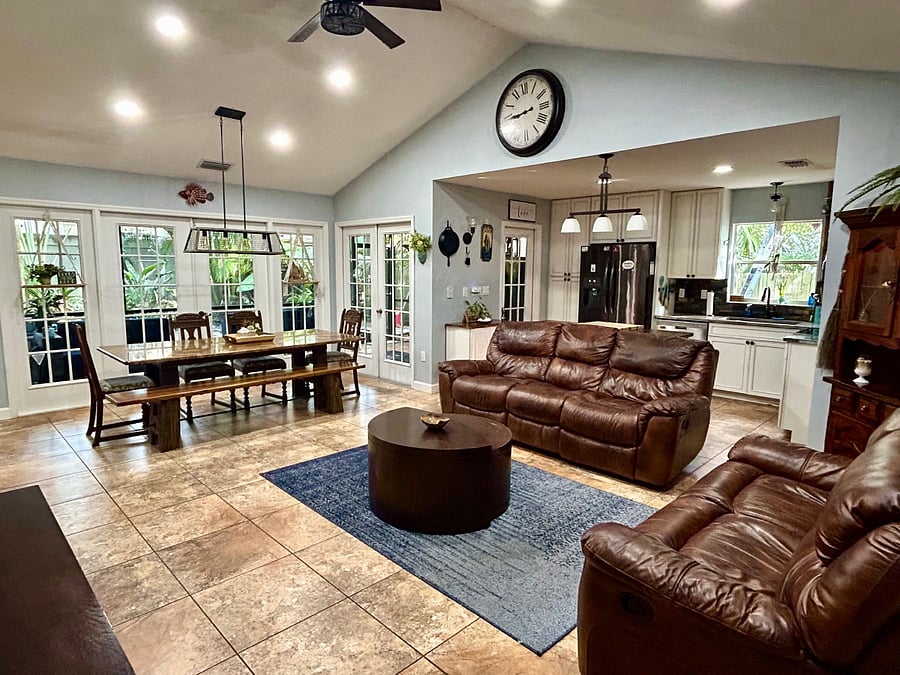 Living room space with 3 seat sofa and love seat, 4 reclining seats total. View of porch, waterfall, and back deck area